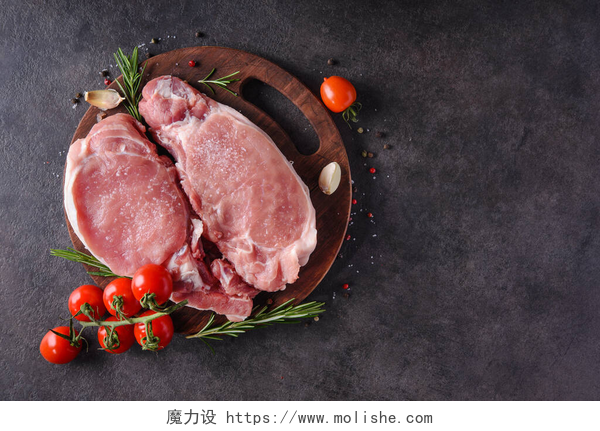 黑色桌子上的牛排生猪排放在有香料和烹调配料的木板上.顶部视图.